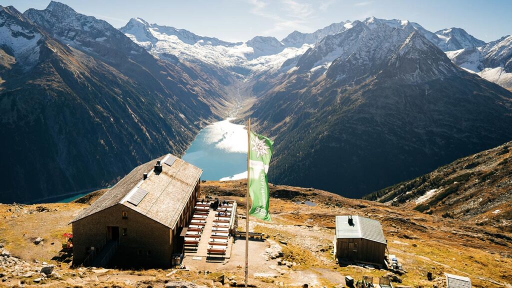 Eine Hütte in den Zillertaler Alpen mit darunter liegendem Stausee. (c) AdobeStock