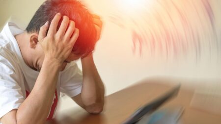 Ein Mann, der seinen Kopf wegen starken Kopfschmerzen auf seinen Hände abstützt. (c) AdobeStock