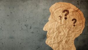 Das Profil eines männlichen Kopfes aus zerknitterten Papier mit Fragezeichen im Gehirn. (c) AdobeStock