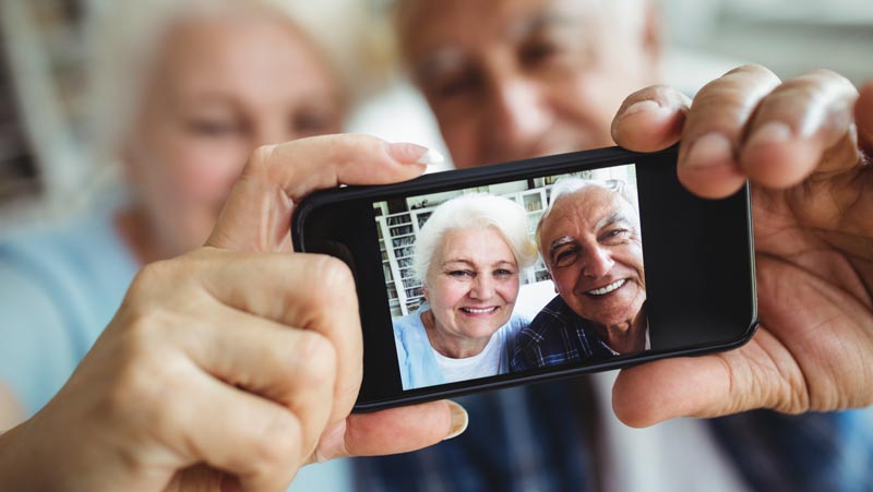 Kommunale Pflegestrategie 2026: Warum die Pflege der Zukunft Nähe braucht 1 Ein älteres Paar macht zuhause ein Selfie mit dem Smartphone – Sinnbild für Lebensfreude und digitale Teilhabe im Alter.(c) AdobeStock