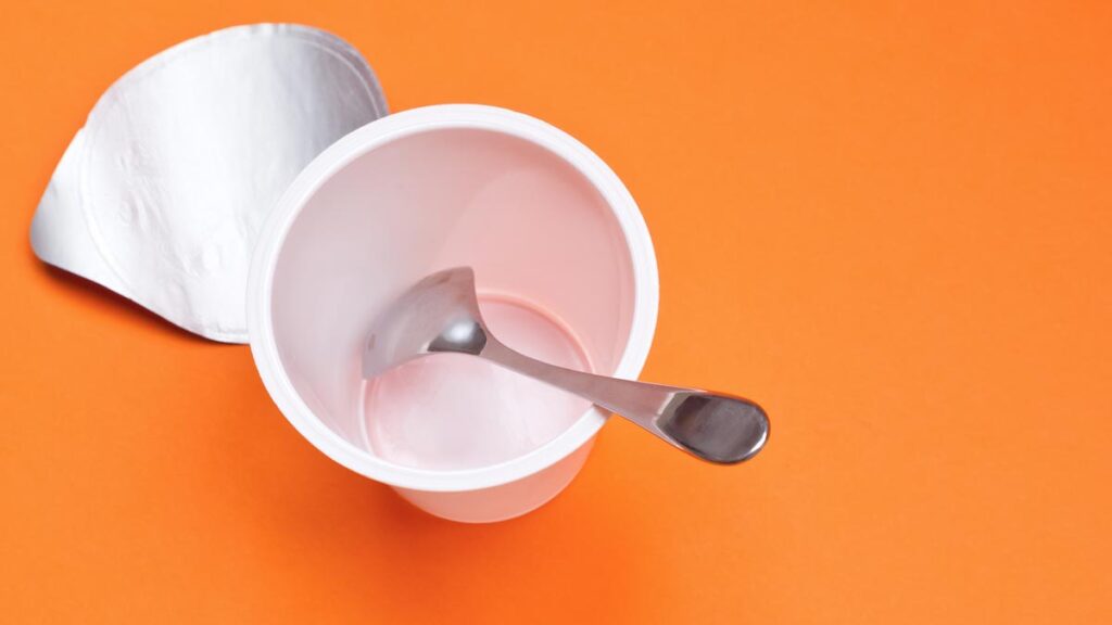 Ein leerer Joghurtbecher, in dem ein Löffel ist, aus der Vogelperspektive. (c) AdobeStock