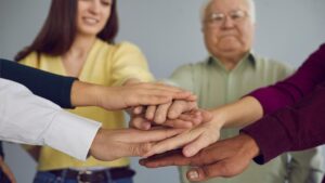 Alte und junge Menschen, die ihre Hände aufeinander legen. (c) AdobeStock