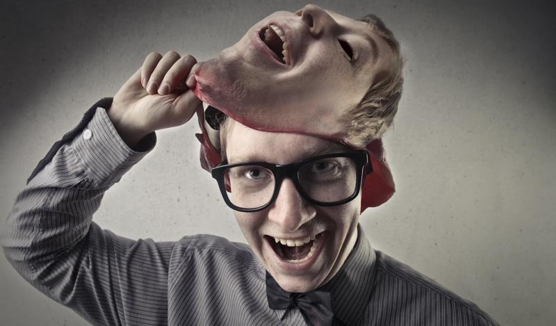 Ein lächelnder Mann mit Brille und Fliege zieht sich eine lebensechte Gummimaske seines eigenen Gesichts vom Kopf, Stichwort Deepfakes.(c) AdobeStock