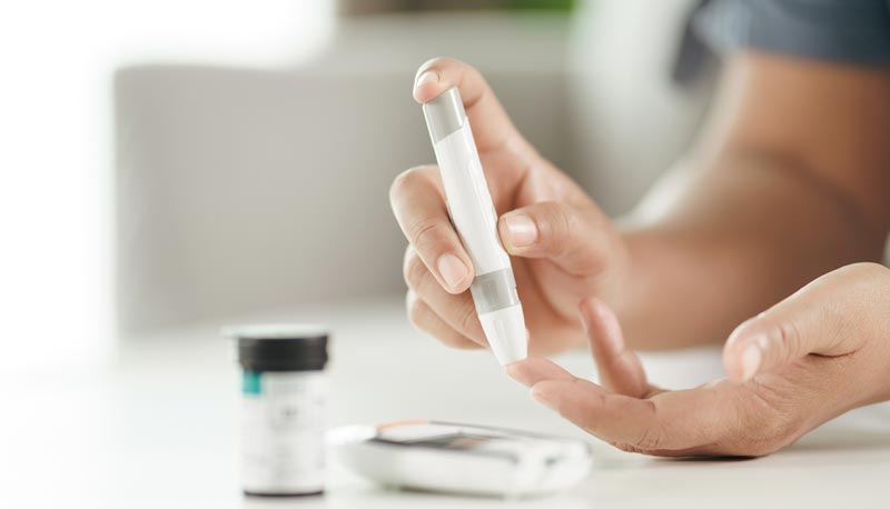 Nahaufnahme einer Person, die mit einer Stechhilfe einen Tropfen Blut für die Blutzuckermessung am Finger gewinnt, Stichwort Diabetes Österreich.(c) AdobeStock