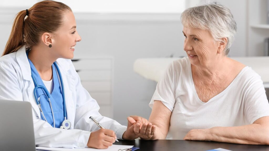 Eine lächelnde Ärztin im weißen Kittel berät eine ältere Patientin in einer hellen Praxis zum Thema Diabetes-Vorsorge. (c) AdobeStock