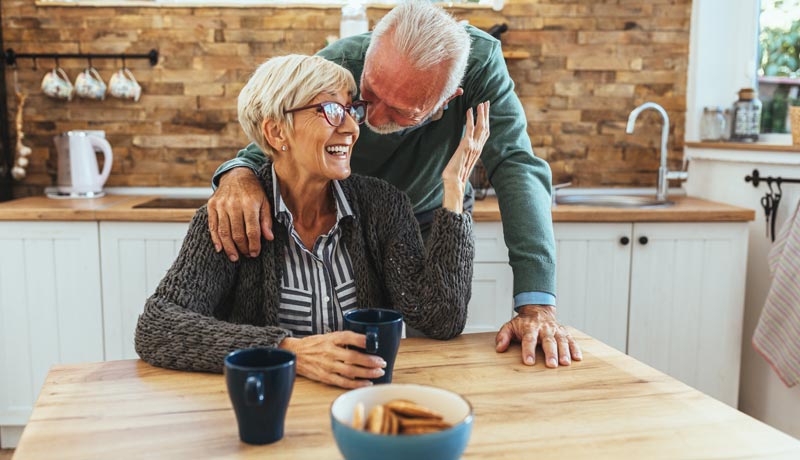 Koffein und Demenzrisiko: 18 Prozent weniger Risiko durch Kaffeegenuss? 2 Ein älteres Paar steht lachend in einer hellen Küche, vor ihnen stehen zwei Tassen Kaffee auf dem Holztisch, Stichwort Koffein und Demenzrisiko.
(c) AdobeStock