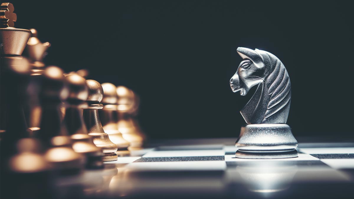 Digital-Marketing: Die nackte Wahrheit nach 25 Jahren an der Front Eine silberne Schachfigur Springer steht im Fokus vor einer unscharfen Reihe goldener Schachfiguren auf einem Brett; Symbol für Marketing-Strategie. (c) AdobeStock