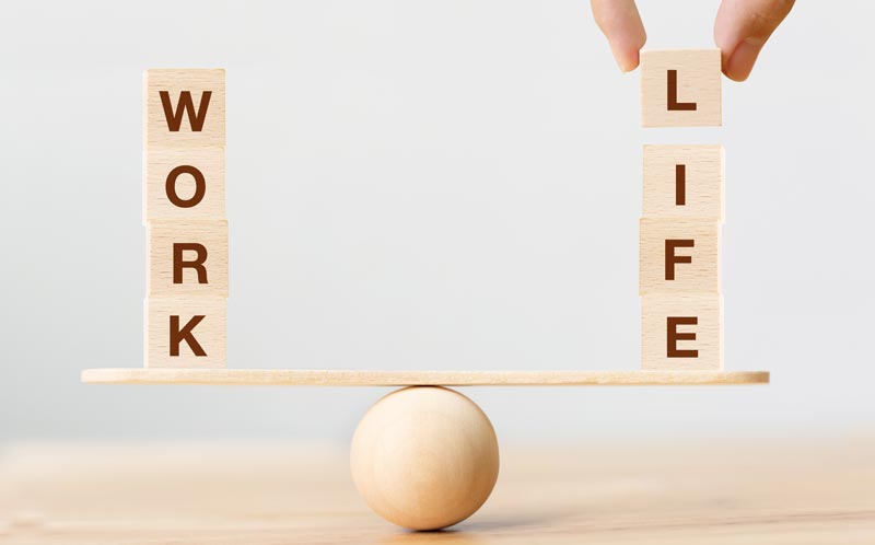 Holzklötze mit der Aufschrift Work und Life balancieren auf einer Wippe, Metapher für Stressmanagement am Arbeitsplatz, Stichwort Burnout Prävention.
(c) AdobeStock