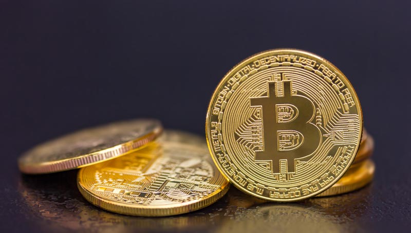 Bitcoin als Altersvorsorge: Digitales Gold oder riskantes Luftschloss für Späteinsteiger? 1 Nahaufnahme einer glänzenden goldenen Bitcoin-Münze, die aufrecht vor einem kleinen Stapel weiterer Krypto-Münzen auf einem dunklen, reflektierenden Untergrund steht, Stichwort Bitcoin als Altersvorsorge.
(c) AdobeStock