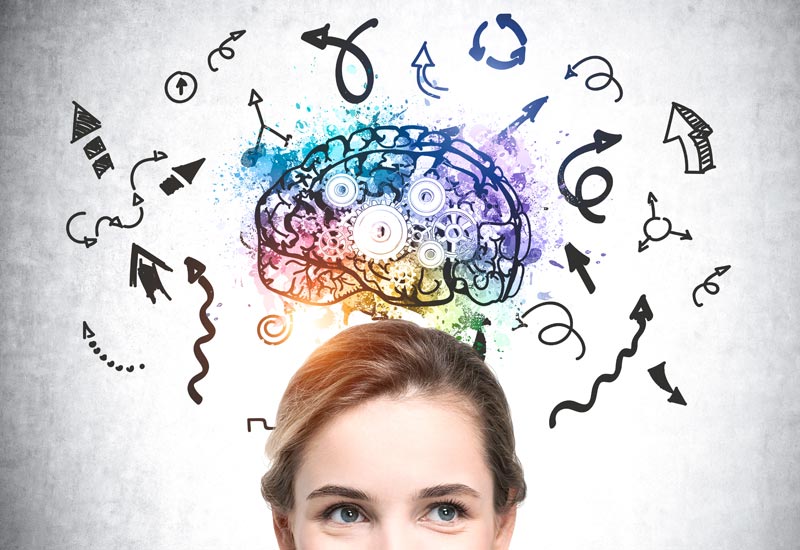 Die obere Gesichtshälfte einer Frau vor einer Betonwand, auf die eine bunte Gehirn-Illustration mit Zahnrädern und vielen chaotischen, geschwungenen Pfeilen gezeichnet ist, Stichwort Neuronale Souveränität.
(c) AdobeStock
