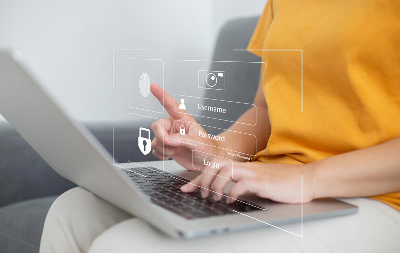 Eine Person im gelben T-Shirt arbeitet am Laptop, über dessen Tastatur eine transparente Login-Maske für Passwörter schwebt – Schutz vor dem Alters-Algorithmus beim Online-Shopping.(c) AdobeStock