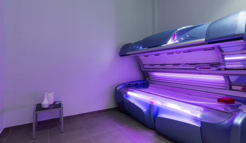 Sonnenschutz ab 50: Warum zwei Drittel im roten Bereich landen 2 Ein leeres Solarium bzw. eine Sonnenbank in einem Behandlungsraum leuchtet intensiv blau und violett, Stichwort Sonnenschutz ab 50.(c) AdobeStock