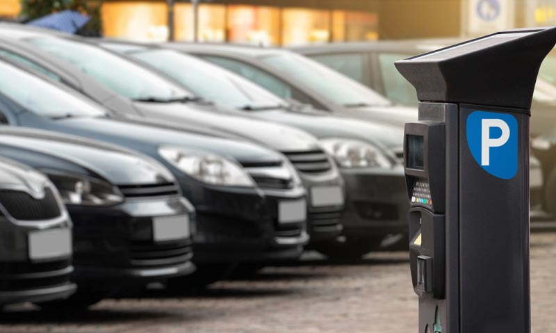Ein Parkpickerl-Automat im öffentlichen Raum mit verschwommenen Autos im Hintergrund, als reales Ziel für die Quishing Betrugsmasche.(c) AdobeStock