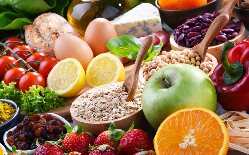 Eine bunte, appetitliche Vielfalt an frischem Gemüse, Obst, Nüssen, Haferflocken und Vollkornprodukten auf einem Tisch, Stichwort Nahrungsergänzungsmittel im Alter.(c) AdobeStock