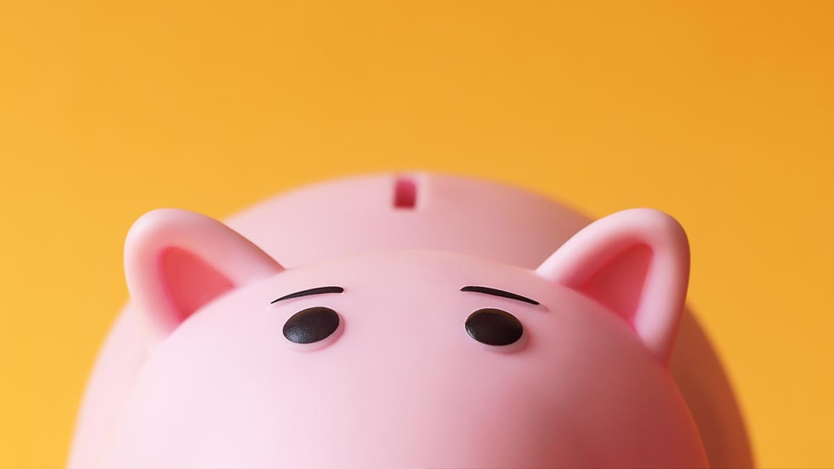 Altersvorsorge 50 Plus: Zwischen Bauspar-Frust und Krypto-Trauma Rosa Sparschwein schaut von unten vorsichtig vor gelbem Hintergrund hervor. (c) AdobeStock