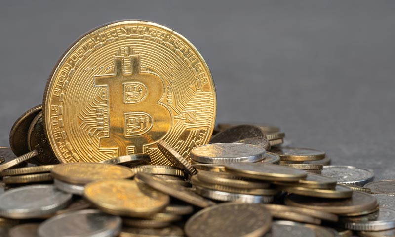 Altersvorsorge 50 Plus: Zwischen Bauspar-Frust und Krypto-Trauma 1 Physische Gold-Bitcoin-Münze thront auf einem Haufen Kleingeld vor grauem Hintergrund.(c) AdobeStock