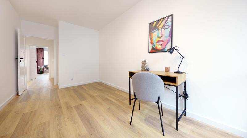 Großes, fast leeres Zimmer mit schlichtem Schreibtisch u. parkettiertem Flur in einer weitläufigen Wohnung.(c) AdobeStock