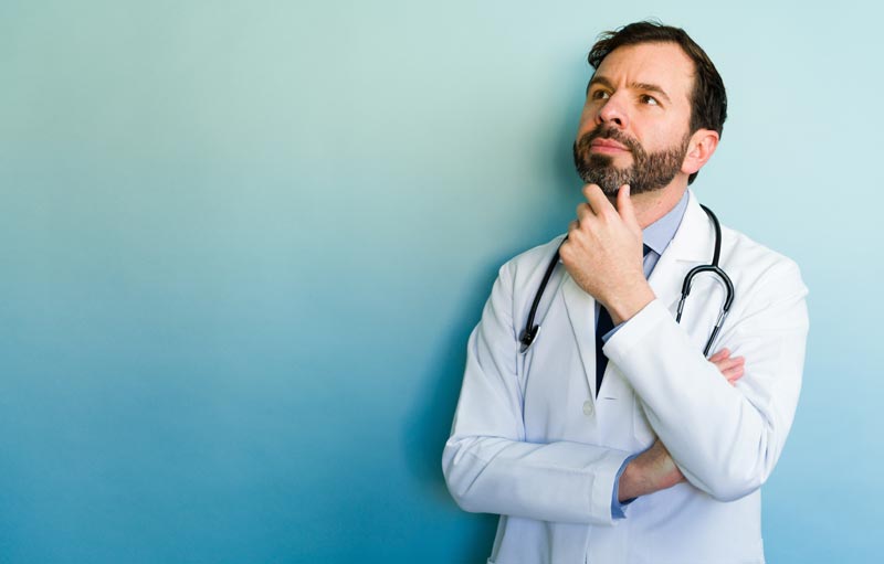 Privatmedizin in Österreich: Das stille Sterben des öffentlichen Kassensystems 1 Arzt im weißen Kittel mit Stethoskop blickt nachdenklich zur Seite.(c) AdobeStock