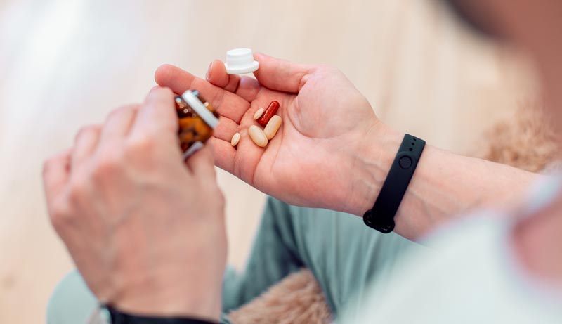 Wechselwirkungen von Medikamenten und Lebensmitteln: Die unsichtbare Gefahr am Teller 1 Hände halten verschiedene Tabletten und Kapseln über einer Medikamentendose.(c) AdobeStock
